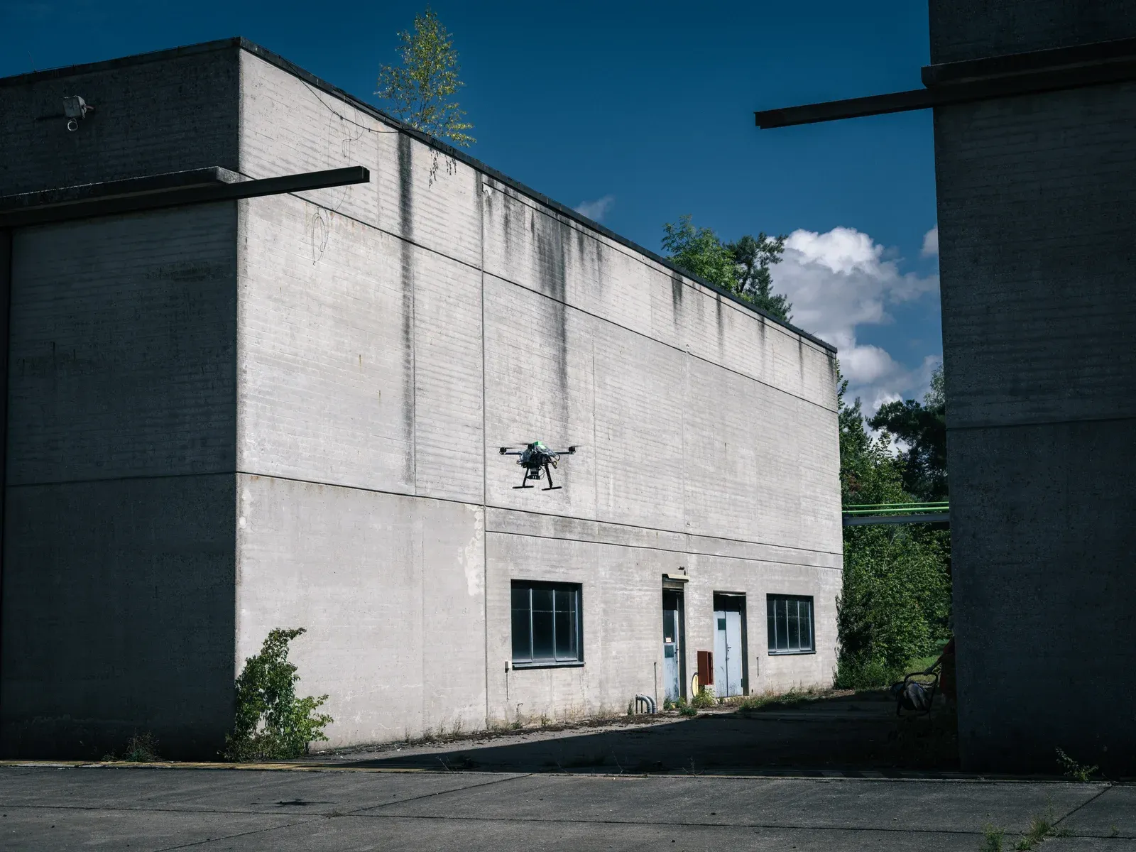 A research quadcopter flying between concrete buildings at the SPRIN-D competition venue.